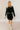 Full body front view of model wearing the Sara Black Long Sleeve T-shirt Dress that has black cotton fabric, mini length, slits on each side, a round neckline, dropped shoulders, and long sleeves.