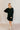 Full body front view of model wearing the Sara Black Long Sleeve T-shirt Dress that has black cotton fabric, mini length, slits on each side, a round neckline, dropped shoulders, and long sleeves.