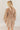 Back view of model wearing the Rosalie Cream Floral Long Sleeve Mini Dress that has cream lightweight fabric with a green and mustard floral print, a smocked upper, a plunge neck, and long puff sleeves.