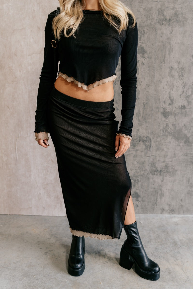 front view of model wearing the Kylie Black & Taupe Mesh Midi Skirt that has black mesh fabric, taupe mesh lining, an elastic waist, a slit on the side, and lettuce hem details.