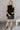 Full body view of model wearing the Miley Black Rhinestone Faux Leather Mini Skirt which features black faux leather fabric, black lining, mini length, rhinestone embellishments, and a monochromatic side zipper with a hook closure.