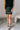 Front view of model wearing the Miley Black Rhinestone Faux Leather Mini Skirt which features black faux leather fabric, black lining, mini length, rhinestone embellishments, and a monochromatic side zipper with a hook closure.