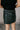 Back view of model wearing the Miley Black Rhinestone Faux Leather Mini Skirt which features black faux leather fabric, black lining, mini length, rhinestone embellishments, and a monochromatic side zipper with a hook closure.