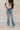 front view of model wearing the The Rooted Denim: Camila Wide Leg Jeans that have light medium denim fabric, a front zipper with a button closure, belt loops, pockets and wide legs.