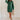 Full body front view of model wearing the Gianna Dark Green Button Front Dress that has dark green corduroy fabric, white stitch detailing, front button closures, a collared neck, chest pockets, and long sleeves.