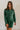 front view of model wearing the Gianna Dark Green Button Front Dress that has dark green corduroy fabric, white stitch detailing, front button closures, a collared neck, chest pockets, and long sleeves.