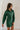 Full body front view of model wearing the Gianna Dark Green Button Front Dress that has dark green corduroy fabric, white stitch detailing, front button closures, a collared neck, chest pockets, and long sleeves.