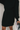 Close up view of model wearing the Laura Black Sweater Belted Dress which features black knit fabric, mini length, a monochromatic adjustable belt at the waistline, a high neckline and long balloon sleeves.