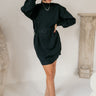 Full body view of model wearing the Laura Black Sweater Belted Dress which features black knit fabric, mini length, a monochromatic adjustable belt at the waistline, a high neckline and long balloon sleeves.