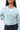Front view of model wearing the Time Is Now Cardigan that has teal, white, and light green knit fabric with a stitched pattern, a button-up front, long sleeves, and a cropped waist. Worn buttoned buttoned over brami.