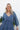Close upper front view of model wearing the Away We Go Dress, that has blue washed fabric, a two-tiered babydoll style, a v neckline, and 3/4 balloon sleeves with elastic wrists.