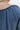 Close-up shoulder view of model wearing the Away We Go Dress, that has blue washed fabric, a two-tiered babydoll style, a v neckline, and 3/4 balloon sleeves with elastic wrists.