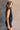 Side view of model wearing the Emily Washed Black Denim Sleeveless Romper which features washed black denim fabric, two front pockets, silver button details, button up front closure, two front chest buttoned pockets, two back pockets, collared neckline an