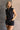 Front view of model wearing the Emily Washed Black Denim Sleeveless Romper which features washed black denim fabric, two front pockets, silver button details, button up front closure, two front chest buttoned pockets, two back pockets, collared neckline a