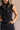 Close up view of model wearing the Emily Washed Black Denim Sleeveless Romper which features washed black denim fabric, two front pockets, silver button details, button up front closure, two front chest buttoned pockets, two back pockets, collared necklin