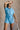 Front view of model wearing the Delilah Washed Sky Blue Short Sleeve Romper which features washed light blue tencel fabric, two front slit pockets, an elastic waistband with a drawstring tie, a right front chest pocket, tortoise button closures, a collare