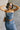 Front view of model wearing the Carrie Washed Denim Slit Strapless Midi Dress which features medium denim wash fabric, brown stitch details, front slit detail, midi length, two front slit pockets, two back pockets, belt loops, frayed hem, straight across 