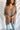 Front view of model wearing the Easy Breezy Top, that has a mocha colored knit material, an open knit design, a V neckline, a long cuffed sleeve, side slits, and a high-low design.