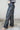 Side view of model wearing the Alexis Black Faux Leather Pants which features black faux leather, front zipper with button closure, two front pockets, two back pockets, belt loops and wide pant legs.