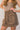 Frontal side view of model wearing the Journey Mocha Brown Cargo Mini Skirt which features taupe brown textured soft fabric, two fornt cargo pocket with zipper closure, elastic waistband with tie and mini length.
