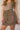 Front side view of model wearing the Journey Mocha Brown Cargo Mini Skirt which features taupe brown textured soft fabric, two fornt cargo pocket with zipper closure, elastic waistband with tie and mini length.