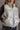 Close front view of model wearing the Winnie Iridescent White Puffer Vest that has a zip-up front with a high neck, front pockets, and adjustable drawstrings.