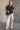 Full body view of model wearing the Presley Black Sleeveless Hoodie Sweatshirt which features black knit fabric, monochrome quarter zip up, high neckline, hoodie attached with drawstring details, one front pocket and sleeveless.