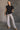 Full body view of model wearing the Presley Black Sleeveless Hoodie Sweatshirt which features black knit fabric, monochrome quarter zip up, high neckline, hoodie attached with drawstring details, one front pocket and sleeveless.