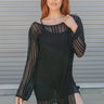 Front view of model wearing the Coast to Coast Cover Up in Black which features open knit black fabric, a mini-length hem, slits on the side, a round neckline and long sleeves.
