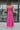Full body back view of model wearing the Coastal Paradise Dress in Pink that has hot pink ribbed fabric, midi length, a round neckline, an elastic waistband, and spaghetti straps