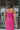 Close back view of model wearing the Coastal Paradise Dress in Pink that has hot pink ribbed fabric, midi length, a round neckline, an elastic waistband, and spaghetti straps