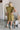 Back view of the Meet Your Match Dress that features a green colored material, a collar neckline, a button-up front, a ruffle sleeve, side pockets, and a mini length.