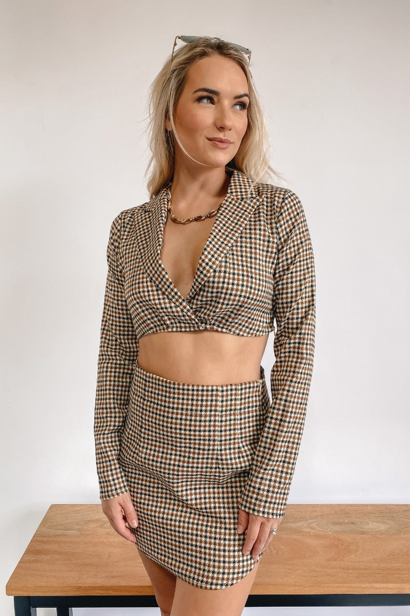 Frontal view of the It Takes Two Crop Blazer that features a beige colored tweed material, a brown and black gingham print, a collar and lapel neckline, a long sleeve, and a cropped fit.