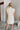 Frontal view of the Heart Breaker Sweater Dress that features an ivory knit material, a turtleneck, a sleeveless design, and a mini length.