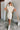 Frontal view of the Heart Breaker Sweater Dress that features an ivory knit material, a turtleneck, a sleeveless design, and a mini length.