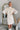 Frontal view of the Heart Breaker Sweater Dress that features an ivory knit material, a turtleneck, a sleeveless design, and a mini length.