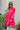 Frontal view of the Wide Open Spaces Mini Dress that features a hot pink material, a round neck with a ruffle trim, a 3/4 button-up front, a long sleeve, a tiered babydoll design, and a flowy fit.