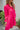 Frontal view of the Wide Open Spaces Mini Dress that features a hot pink material, a round neck with a ruffle trim, a 3/4 button-up front, a long sleeve, a tiered babydoll design, and a flowy fit.