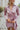 Frontal view of the Risk It All Dress that features a dusty pink silk material, a collar neck, a V surplice neckline, a long cuffed sleeve, a wrap front with a tie detail, and a mini length.