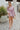 Frontal view of the Risk It All Dress that features a dusty pink silk material, a collar neck, a V surplice neckline, a long cuffed sleeve, a wrap front with a tie detail, and a mini length.