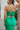 Back view of the Call You Mine Midi Dress In Green that features a green colored silk material, a cowl neckline, a sleeveless design with thin adjustable straps, a side slit, and a midi length.