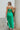 Back view of the Call You Mine Midi Dress In Green that features a green colored silk material, a cowl neckline, a sleeveless design with thin adjustable straps, a side slit, and a midi length.