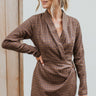 Frontal view of the Next Century Dress that features a brown tweed material, a navy gingham print, a lapel surplice neckline, a long sleeve, a wrap front with a tortoiseshell buckle, and a mini length.