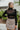 Frontal view of the Mesh Well Together Bodysuit that features a black knit material, a high turtleneck, a long sleeve, a sweetheart neckline with mesh material at the chest, a back zipper closure, and a thong bottom with a snap closure.