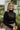 Frontal view of the Mesh Well Together Bodysuit that features a black knit material, a high turtleneck, a long sleeve, a sweetheart neckline with mesh material at the chest, a back zipper closure, and a thong bottom with a snap closure.