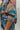 Frontal view of the Signature Move Top that features a multi-colored silk material with a watercolor design, a collar neck, long cuffed sleeves, a button-up front, and a front pocket.