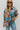 Frontal view of the Signature Move Top that features a multi-colored silk material with a watercolor design, a collar neck, long cuffed sleeves, a button-up front, and a front pocket.