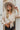 Frontal view of the On Your Mark Top that features a collared neckline, a monochromatic checkered print, long cuffed sleeves, a gold button-up front, and a high-low design.