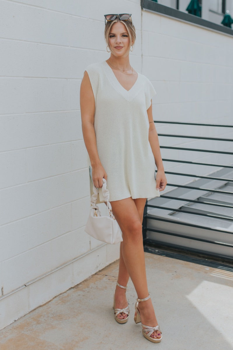 Full body view of model wearing the It's Show Time Vest in Cream which features cream cable knit fabric, slits on each side, v-neckline and sleeveless.