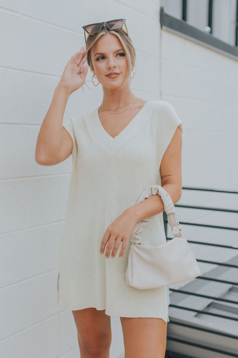 Front view of model wearing the It's Show Time Vest in Cream which features cream cable knit fabric, slits on each side, v-neckline and sleeveless.